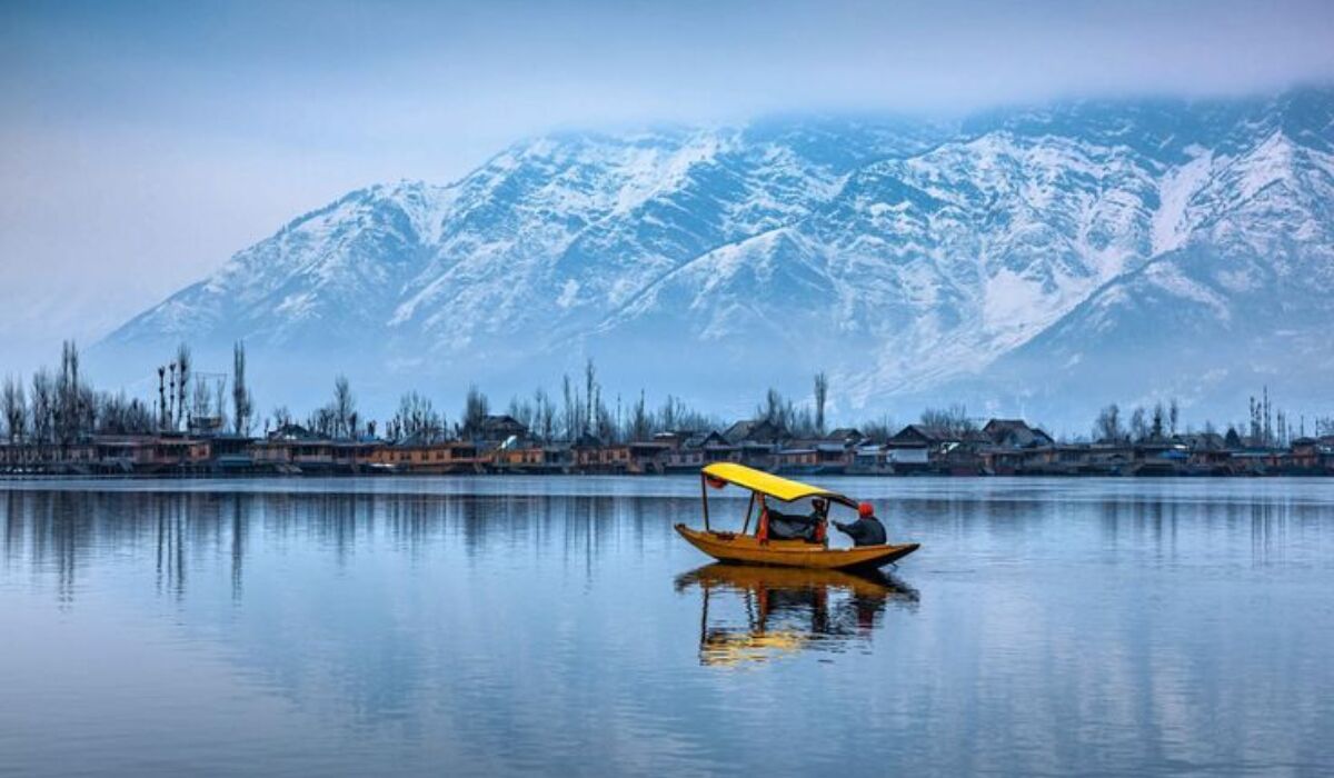 Scenic Kashmir landscape with snow-capped mountains, green valleys, and a lake on a 7-day Kashmir itinerary.